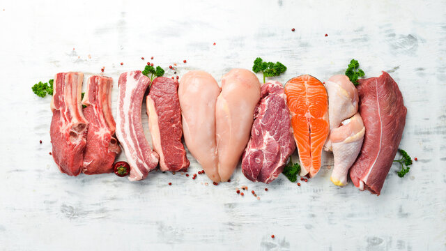 Banner. Raw meat steaks salmon, beef and chicken on a white wooden background. Organic food. Top view.