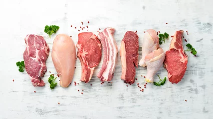 Fotobehang Banner. Raw meat steaks salmon, beef and chicken on a white wooden background. Organic food. Top view. © Yaruniv-Studio