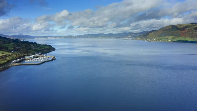 Carlingford Lough, Louth, Ireland, October 2021. Drone gradually ascends while facing west towards Carlingford Marina with Warrenpoint in Northern Ireland.