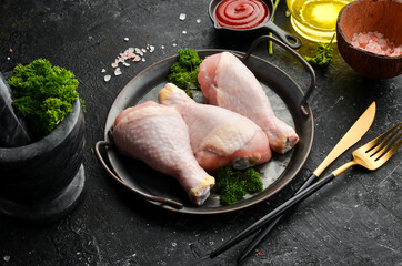 Chicken meat. Raw fresh chicken drumsticks on black slate stone background. Top view. Raw meat.