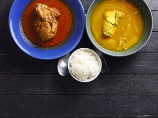 Top view of Thai meal - rice , sour spicy soup and chicken muslim curry on black table
