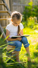 A little girl reading a book outdoors