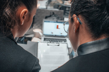 Chicas abogadas concentradas trabajando en equipo escribiendo ideas y planteamientos con sus documentos y contratos junto con su ordenador laptop en una cafeteria para terminar su trabajo