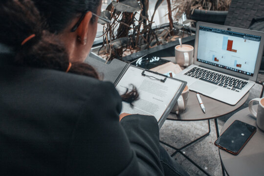 Muchachas abogadas observando y trabajando en equipo escribiendo planteamientos con sus documentos y contratos junto con su ordenador laptop en una cafeteria para terminar su trabajo