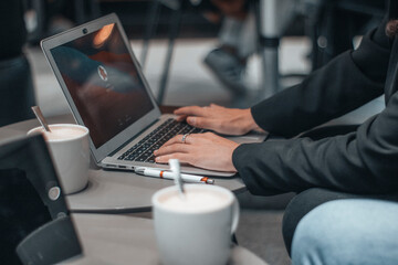 Mujer formal iniciando sesión para escribir ideas y planteamientos en su ordenador laptop en una cafeteria de su ciudad tomando café por la mañana para terminar su trabajo