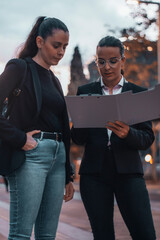 Secretarias de cabello moreno formales con seriedad de pie revisando sus apuntes con contratos en...