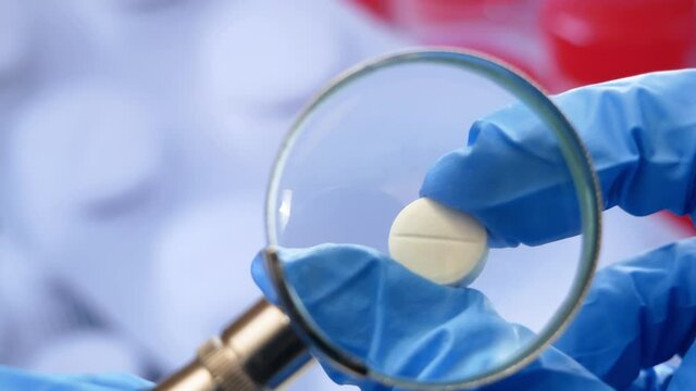 magnifying glass, pills and tablets on blue background. checking ingredients and effectiveness of medicine
