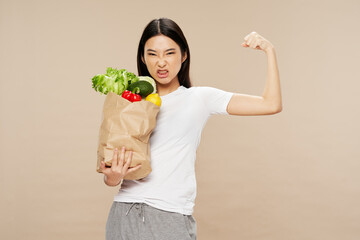 woman with a package of products on a beige background shows the muscles of the arms diet calories