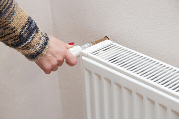 Woman adjusting thermostat radiator valve.
