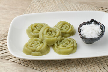 Kue Lumpang Pandan or Kue IJo, Indonesian traditional food with springy texture, made from sago flour and rice flour, sugar and pandan. Served in white plate, selective focus image.
