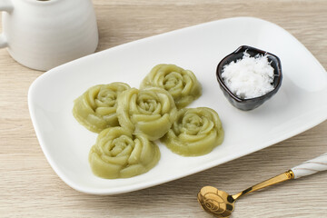 Kue Lumpang Pandan or Kue IJo, Indonesian traditional food with springy texture, made from sago flour and rice flour, sugar and pandan. Served in white plate, selective focus image.
