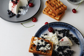 delicious healthy breakfast. Belgian soft waffles with curd cheese cream and blueberry cherries lie white blue plate view from the top. Delicious still life