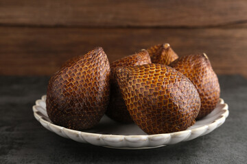 Salak or thorny palm or snake fruit (Salacca zalacca) is a species of palm tree. Served in white plate on dark background. Selective focus image. Close up.
