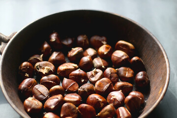 Pan filled with chestnuts on dark background. Selective focus.