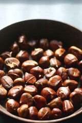 Pan filled with chestnuts on dark background. Selective focus.