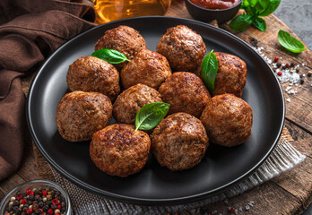 Meatballs with fresh basil on a wooden board.