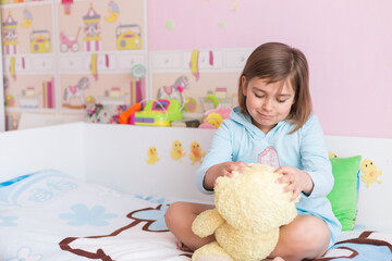 Adorable funny little girl with teddy bear in bedroom. Childhood leisure