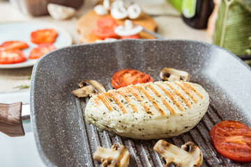 Cyprus fried halloumi cheese with red tomatoes and champignons. Balanced food. Cooking on grill pan