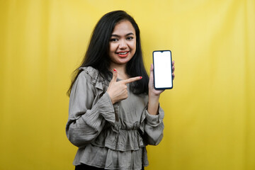 Naklejka premium Beautiful young woman with hands holding smartphone with blank or white screen, promoting app, promoting something, cheerful and confident, advertisement, isolated