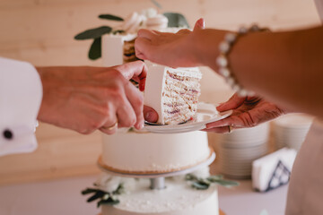 People cutting delicious white wedding cake with macaroons