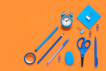 Back to school, business office education concept. Assortment of blue supplies, crayons, clock, pens on a table. Copy space background, top view flat lay overhead. Blue and Orange colors.