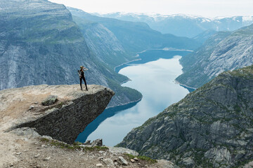 Fototapeta na wymiar A young woman poses on Trolltunga cliff, Vestland county, Norway