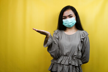 Beautiful young woman wearing a mask with open arms in empty space, presenting something, isolated