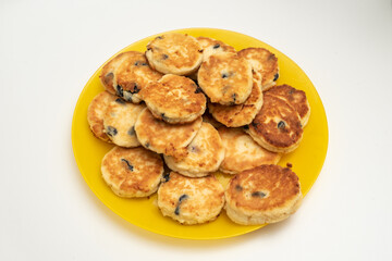 Full yellow plate of cottage cheese pancakes on white background