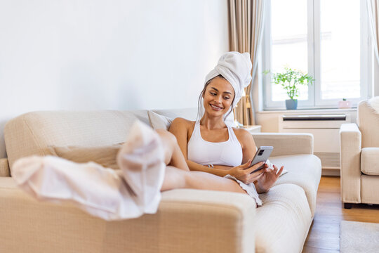 Moisturizing foot mask, for dry heels of the feet. Woman wearing disposable moisturizing socks for the legs. After a shower, a girl wrapped in a towel uses moisturizing foot mask. Cosmetic trends