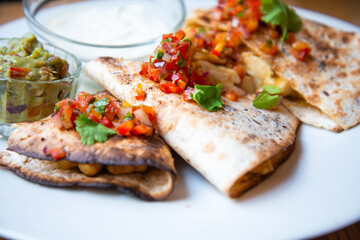 Delicious Mexican quesallidas made with chicken, tomato pieces and served with guacamole sauce.