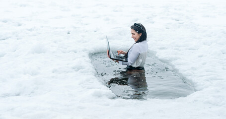 Girl with laptop in frozen lake ice hole. Woman hardening the body in cold water. Good immunity is protection against many diseases.