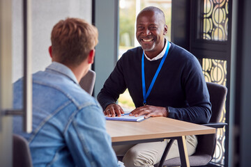 Male University Or College Student Having Individual Meeting With Tutor Or Counsellor