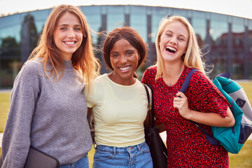 Portrait Of Three Female University Or College Student Standing Outdoors By Modern Campus Building