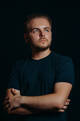 Naklejka premium Attractive stylish guy stands with arms crossed and looks up and thinks about bright future. Serious man ponders. Smart man with own opinion. Man develops idea. Business man. Studio shooting