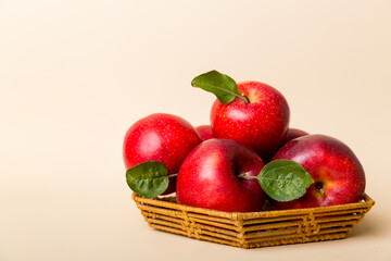 Ripe garden apple fruits with leaves in basket on wooden table. Top view flat lay with copy space