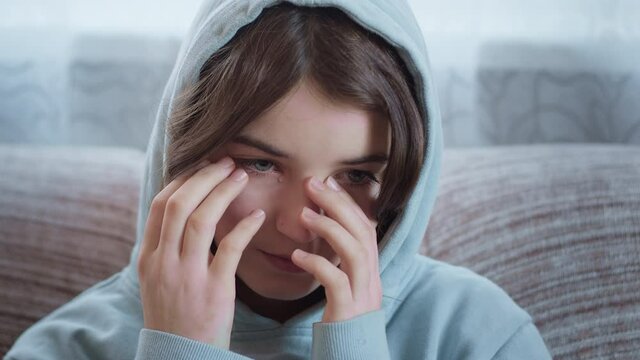 The face of a crying girl with tears in her eyes. Depression and sadness in a teenage schoolgirl.