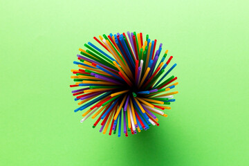 Top view of many multicolored plastic cocktail tubes in a glass. Drinking straws of bright colors Isolated on white background