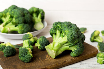 fresh green broccoli on wooden cutting board with knife. Broccoli cabbage leaves. light background. Flat lay