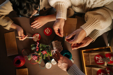 High angle view of unrecognizable family making Christmas advent calendar together sitting at table...