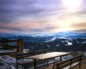 Wooden table with a bench on the veranda of a high-altitude cafe opposite the Elbrus and mountains of the Caucasus Range