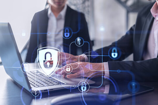 Two businesspeople in formal wear working on the project to protect cyber security of international company using laptop. Padlock Hologram icons. Teamwork concept.