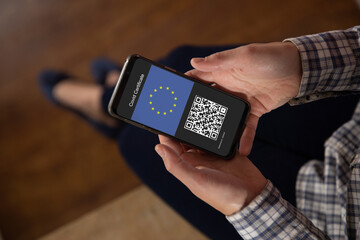 Woman holding smartphone with covid 19 vaccine passport