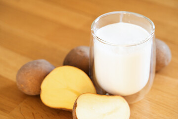 Potato milk photo on wooden background. Glass of alternative milk. Plant based vegetarian beverage. Lactose free drink