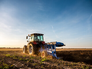 Farmer in tractor plowing preparing stubble field cultivating for seeding crops. © oticki
