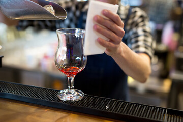 The bartender in the restaurant pours ice into a cocktail glass