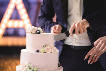 The bride and groom cut a gorgeous wedding cake at a banquet.