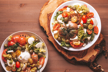 Mediterranean style tomato heirloom salad in white plate on wooden table