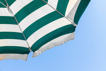 Part of the beach umbrella with white and green stripes in the middle of summer. Bottom view.