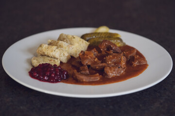 ready to eat - delicious goulash of chamois meat with napkin dumplings, pickles and cranberries
