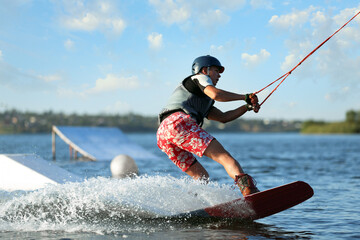 Teenage boy wakeboarding on river. Extreme water sport
